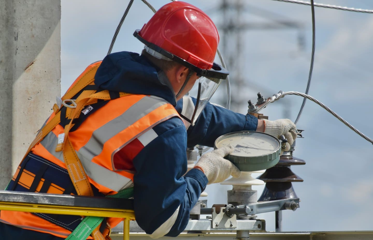 Técnico con chaleco de seguridad ajusta equipo eléctrico al aire libre.