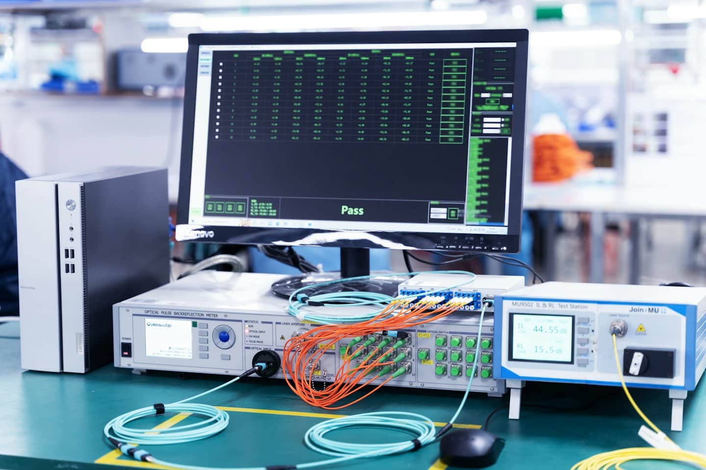 Equipo de prueba de fibra óptica con cables y resultados aprobados en pantalla.