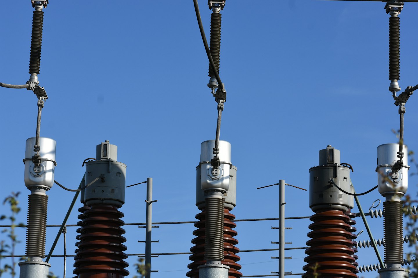 Aisladores eléctricos marrones y componentes metálicos de una línea eléctrica.
